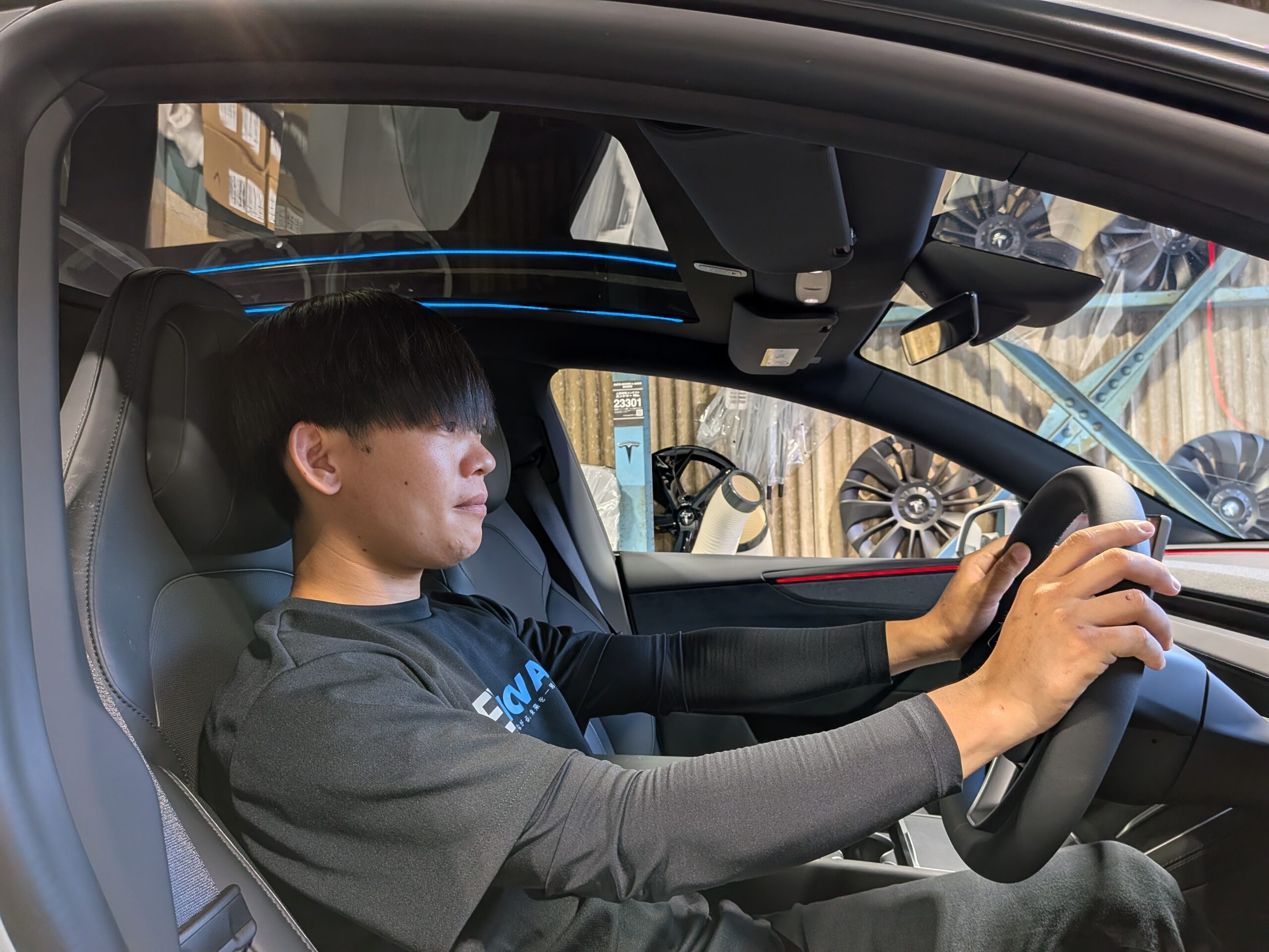 Teslaの運転席でハンドルを握り操作を確認するEVNOVAスタッフ